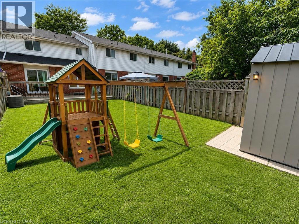 Spacious rear yard featuring an expansive lawn, full-height privacy fencing, and a built-in outdoor storage shed - 41 Edgemere Drive, Cambridge, ON - Outdoor