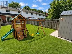 Spacious rear yard featuring an expansive lawn, full-height privacy fencing, and a built-in outdoor storage shed -