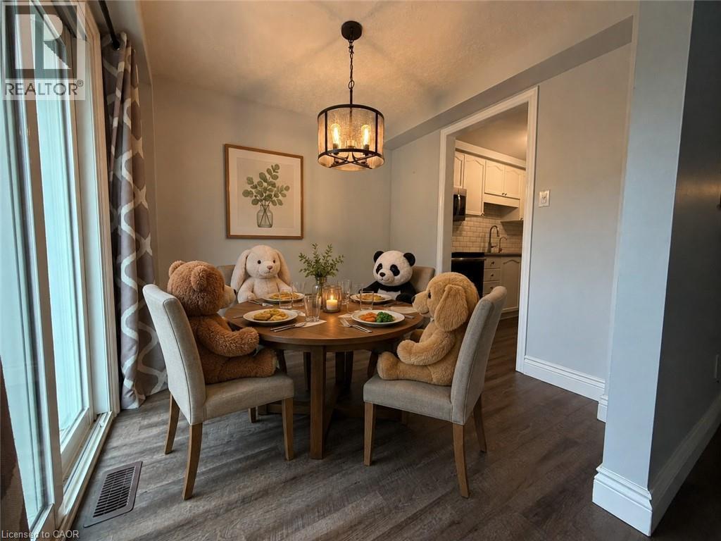 Dining area featuring wood-finish flooring, a contemporary chandelier, and a framed botanical print - 41 Edgemere Drive, Cambridge, ON - Indoor Photo Showing Dining Room
