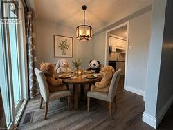 Dining area featuring wood-finish flooring, a contemporary chandelier, and a framed botanical print -