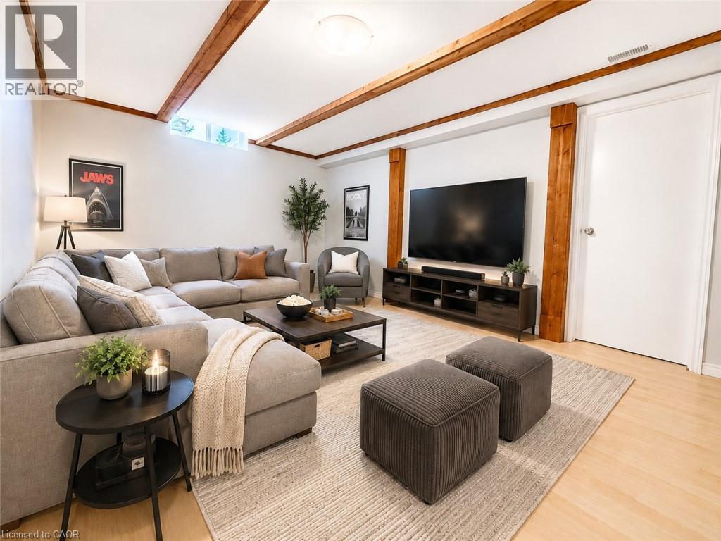 Spacious entertainment area featuring exposed wood beams, light wood-finish flooring, and a large media console - 41 Edgemere Drive, Cambridge, ON - Indoor Photo Showing Living Room