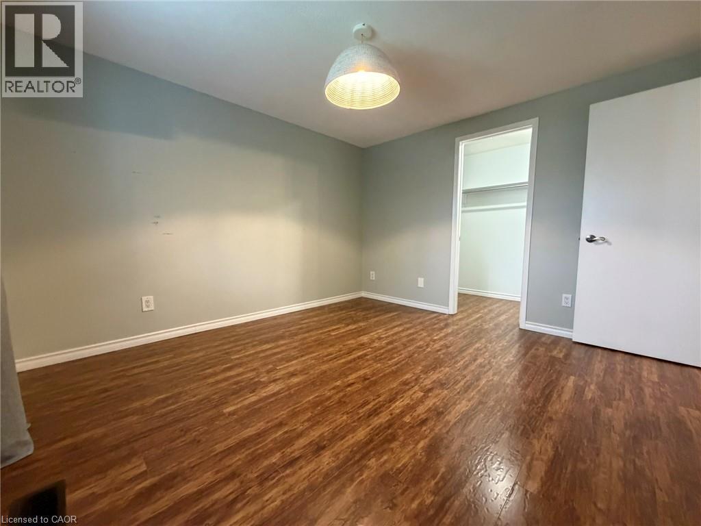 Room featuring wood-finish flooring, light-toned wall paint, white baseboards, and a ceiling light fixture - 41 Edgemere Drive, Cambridge, ON - Indoor Photo Showing Other Room