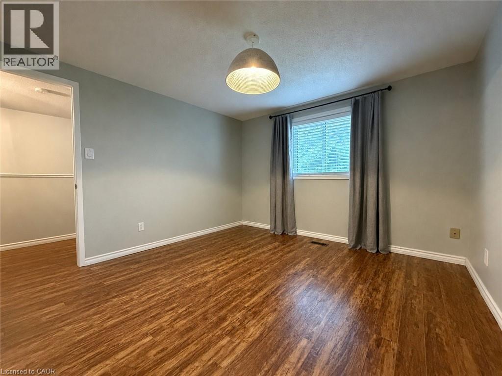 Room featuring wood-finish flooring, light grey walls, white baseboards, and a window with blinds and drapes - 41 Edgemere Drive, Cambridge, ON - Indoor Photo Showing Other Room
