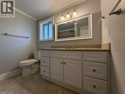 Bathroom vanity featuring a light-toned countertop, white cabinetry, and a framed mirror with overhead lighting -