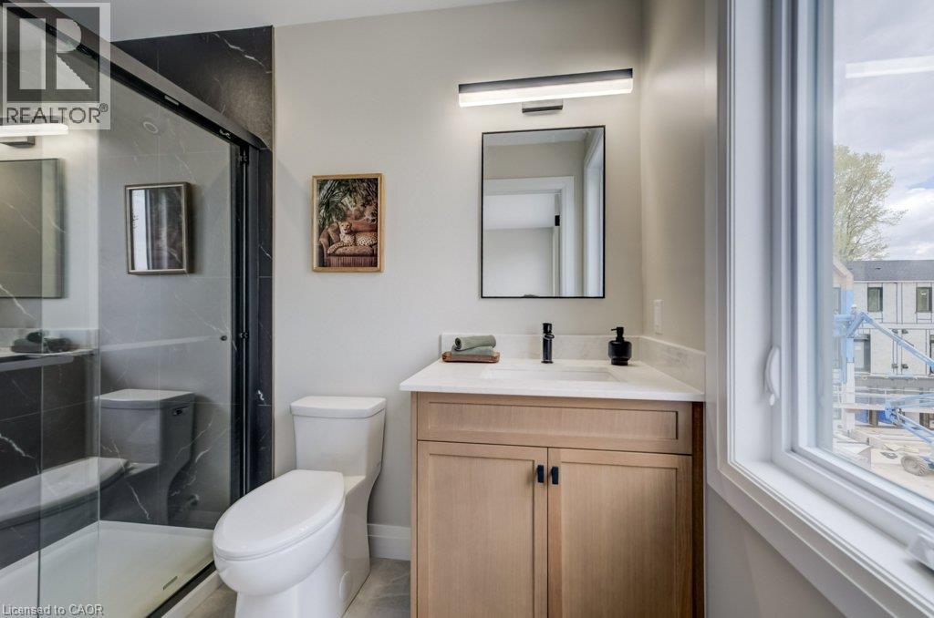 Modern bathroom featuring a glass-enclosed shower with dark marble-look tile, a light wood-finish vanity with a light countertop, a rectangular sink, and a black faucet - 210 Heritage Drive Unit# Upper, Kitchener, ON - Indoor Photo Showing Bathroom