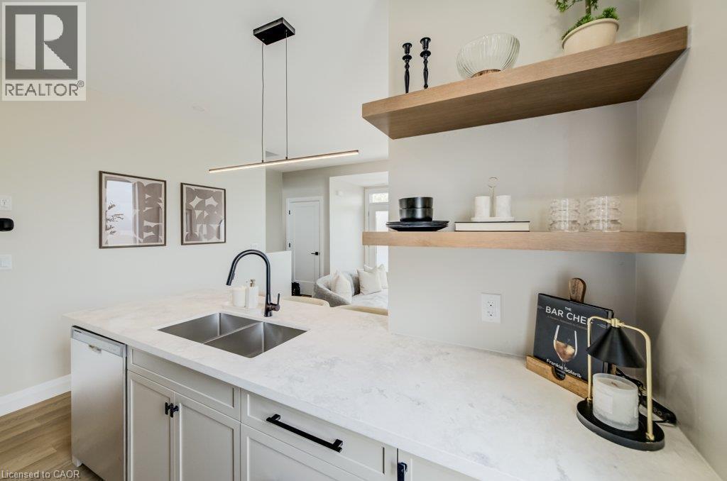 Kitchen island featuring a dual basin sink with a matte black gooseneck faucet, white stone-finish countertop, and integrated under-counter appliance - 210 Heritage Drive Unit# Upper, Kitchener, ON - Indoor Photo Showing Kitchen With Double Sink