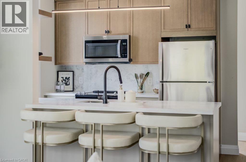 Compact kitchen area featuring wood-finish cabinetry, stainless steel appliances, a white countertop, and a black gooseneck faucet - 210 Heritage Drive Unit# Upper, Kitchener, ON - Indoor