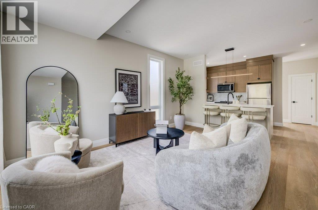 Open-concept living area featuring wood-finish flooring, recessed lighting, and a kitchen with an island, light-toned cabinetry, and stainless steel appliances - 210 Heritage Drive Unit# Upper, Kitchener, ON - Indoor Photo Showing Living Room