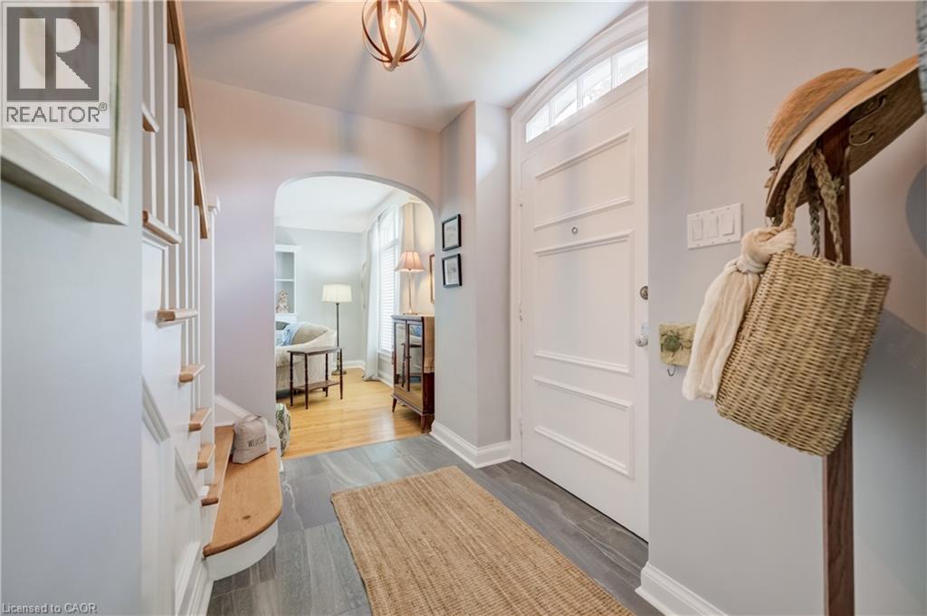 Entryway featuring wood-finish flooring, a staircase with wood treads, an arched doorway, a white paneled door with an arched transom, and a wood orb-style ceiling fixture - 314 Glasgow Street, Kitchener, ON - Indoor Photo Showing Other Room