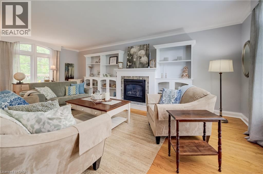 Spacious living area featuring hardwood flooring, a fireplace with a dark tile surround, and custom built-in shelving - 314 Glasgow Street, Kitchener, ON - Indoor Photo Showing Living Room With Fireplace