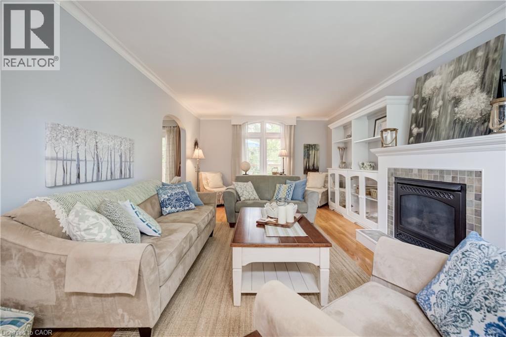 Expansive living area featuring light wood-finish flooring, a built-in fireplace with a tiled surround, and integrated custom cabinetry with shelving - 314 Glasgow Street, Kitchener, ON - Indoor Photo Showing Living Room With Fireplace