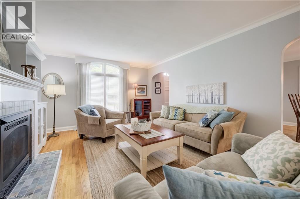 Living area with wood-finish flooring, a white mantel fireplace featuring a patterned tile surround, and an arched window with blinds - 314 Glasgow Street, Kitchener, ON - Indoor Photo Showing Living Room With Fireplace
