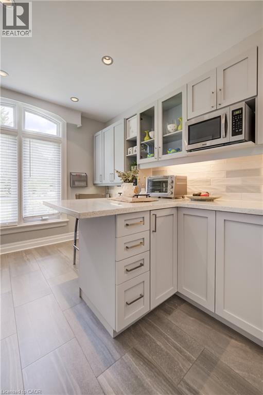 Kitchen featuring light gray cabinetry, built-in microwave, wood-finish tile flooring, recessed ceiling lighting, and an arched window - 314 Glasgow Street, Kitchener, ON - Indoor Photo Showing Kitchen
