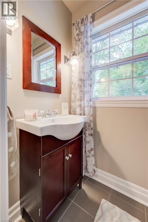 Bathroom vanity with a white integrated sink, dark wood-finish cabinetry, chrome faucet, and decorative mirror - 314 Glasgow Street, Kitchener, ON - Indoor Photo Showing Bathroom