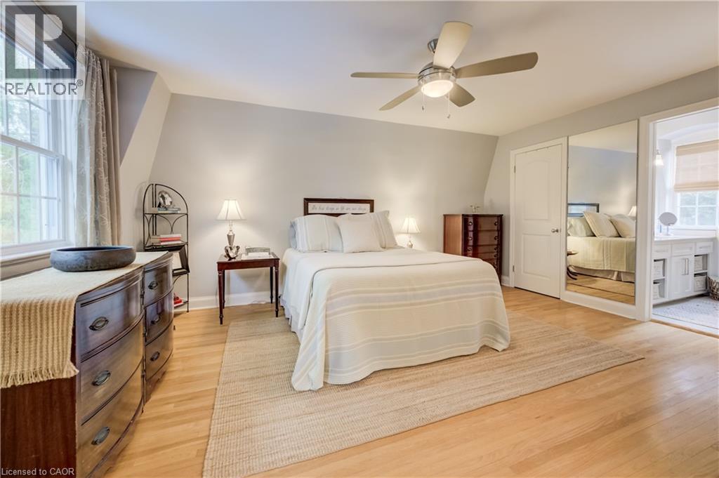 Spacious bedroom featuring light wood-finish flooring, a large window, a ceiling fan with integrated lighting, and a mirrored closet door - 314 Glasgow Street, Kitchener, ON - Indoor Photo Showing Bedroom