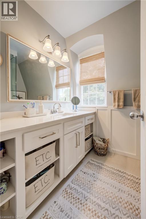 Bathroom featuring a single vanity with a white countertop and undermount sink, white cabinetry with brushed nickel hardware, a rectangular framed mirror, and a wall-mounted light fixture with four sc - 314 Glasgow Street, Kitchener, ON - Indoor Photo Showing Bathroom