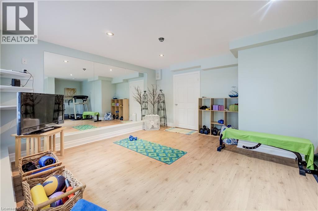 Spacious interior room featuring light wood-finish flooring, a full-wall mirror, recessed lighting, and light blue wall tones - 314 Glasgow Street, Kitchener, ON - Indoor