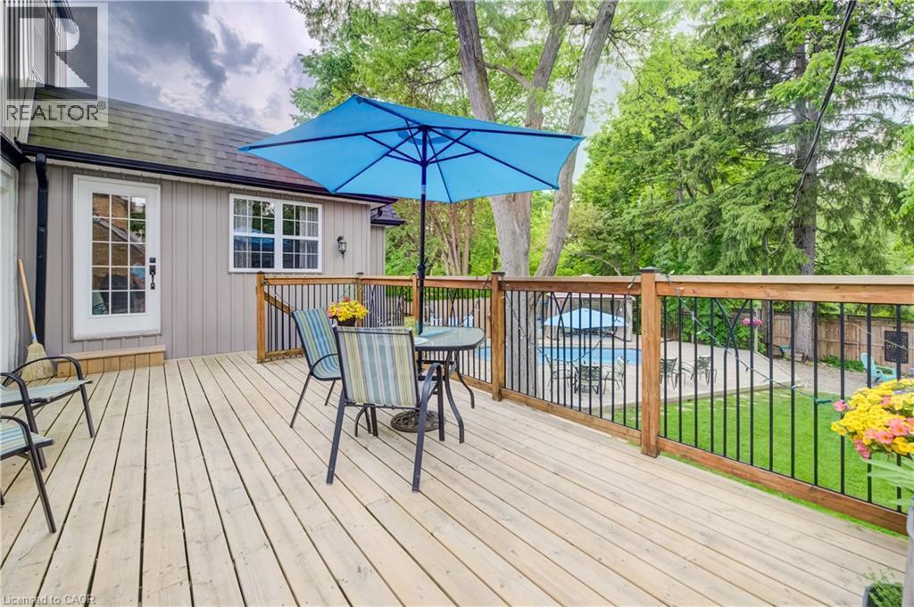 Spacious wood deck with wood and black metal railings, offering an exterior entry door with glass panes, a window with white trim, and a surrounding green lawn - 314 Glasgow Street, Kitchener, ON - Outdoor With Deck Patio Veranda With Exterior