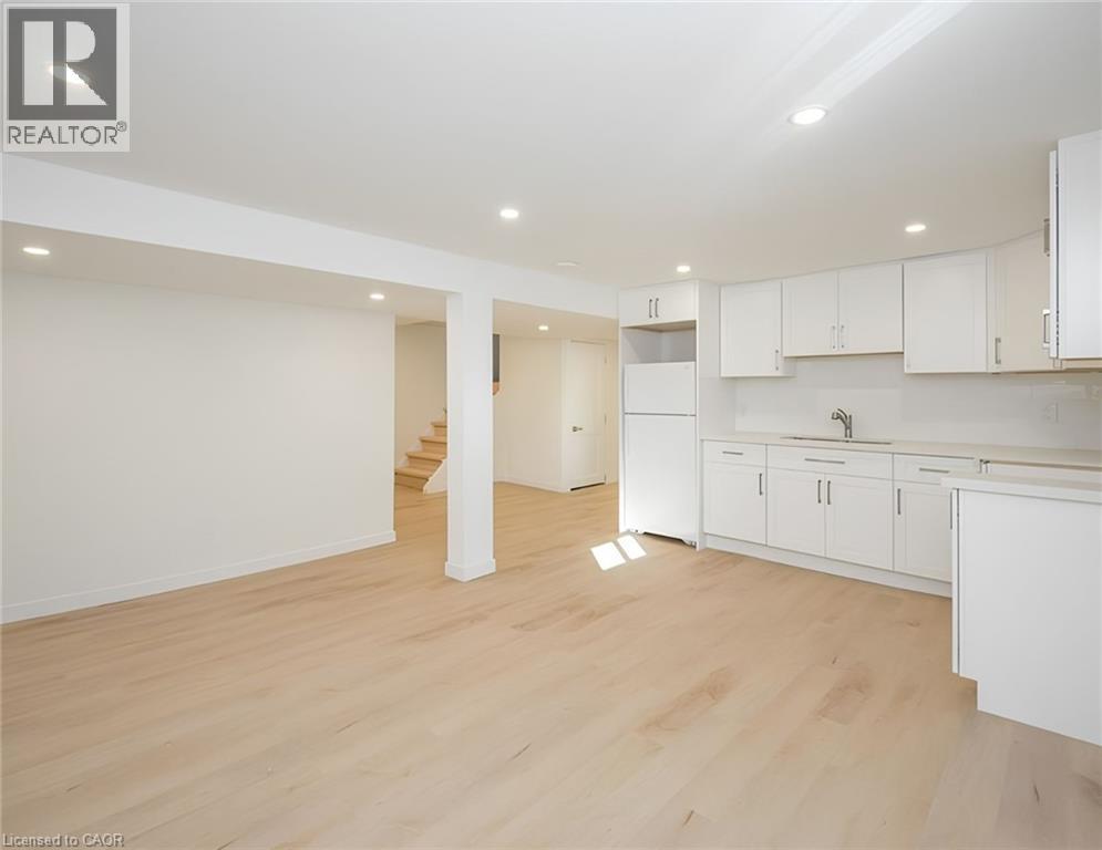 Open-concept kitchen and dining area featuring light wood-finish flooring, white cabinetry, integrated sink, and recessed lighting - 781 Ninth Avenue Unit# Lower, Hamilton, ON - Indoor Photo Showing Kitchen