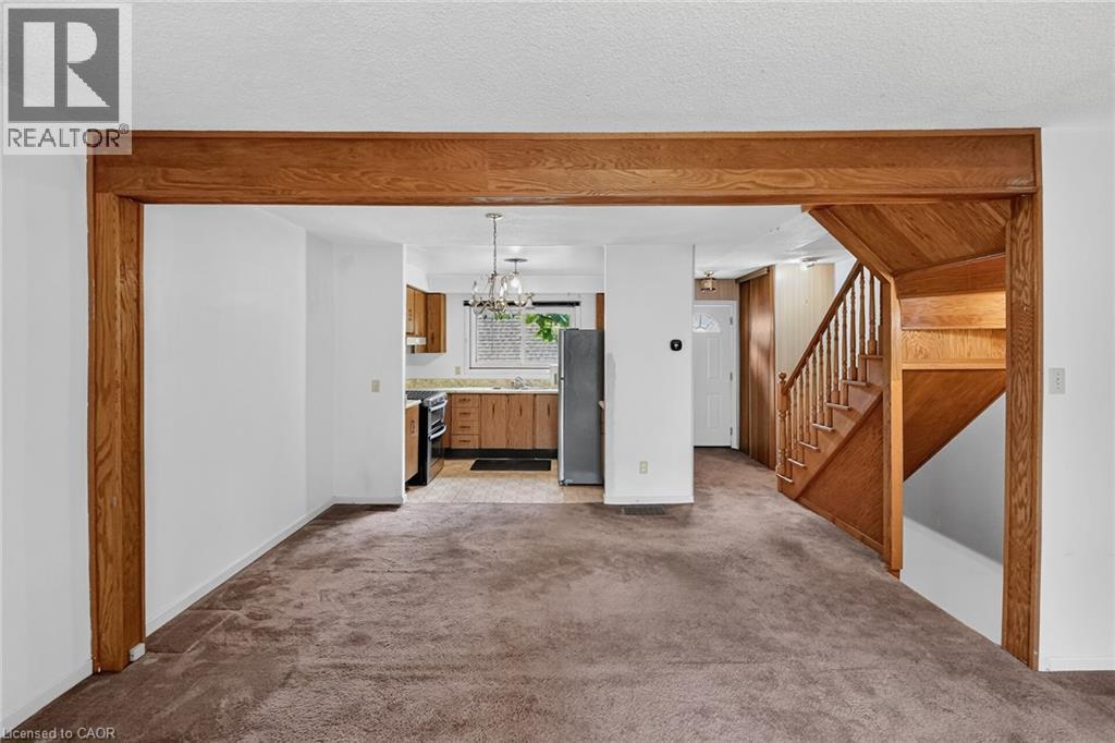 Living area featuring carpet flooring, natural wood beam entryway, and natural wood staircase - 125 Bonaventure Drive Unit# 50, Hamilton, ON - Indoor