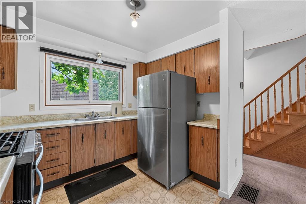 Kitchen featuring wood-finish cabinetry, stainless steel refrigerator, and a gas range - 125 Bonaventure Drive Unit# 50, Hamilton, ON - Indoor Photo Showing Kitchen With Double Sink