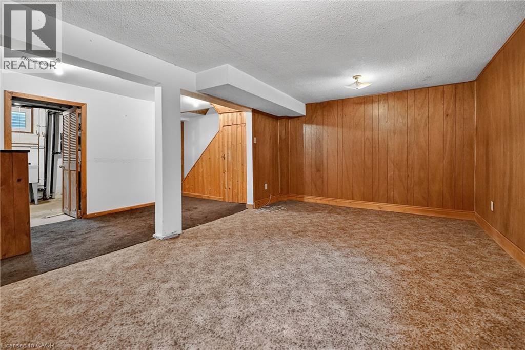 Spacious room featuring wood paneling, white painted walls, and textured carpeting - 125 Bonaventure Drive Unit# 50, Hamilton, ON - Indoor