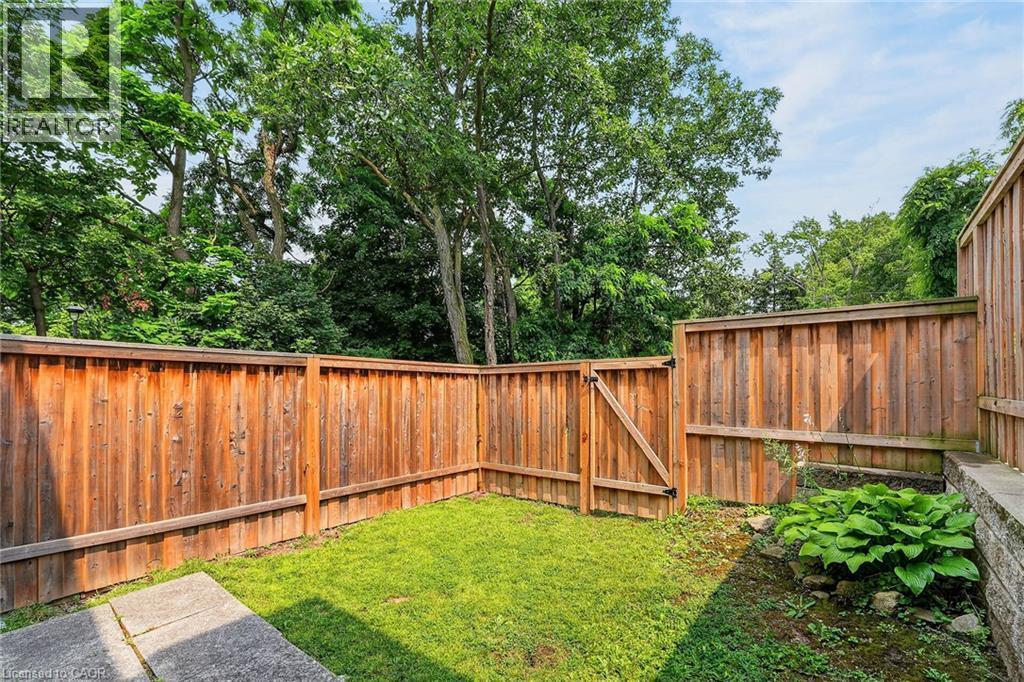 Private backyard space featuring a wood fence, a gate, and a lush green lawn - 125 Bonaventure Drive Unit# 50, Hamilton, ON - Outdoor