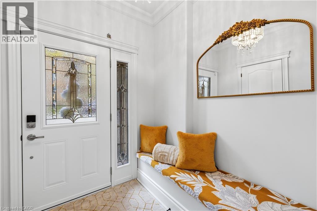 Entryway featuring a white paneled door with decorative leaded glass, an accompanying sidelight with patterned glass, a built-in bench with storage, and patterned floor tiling - 199 Hunter Street W, Hamilton, ON - Indoor Photo Showing Other Room
