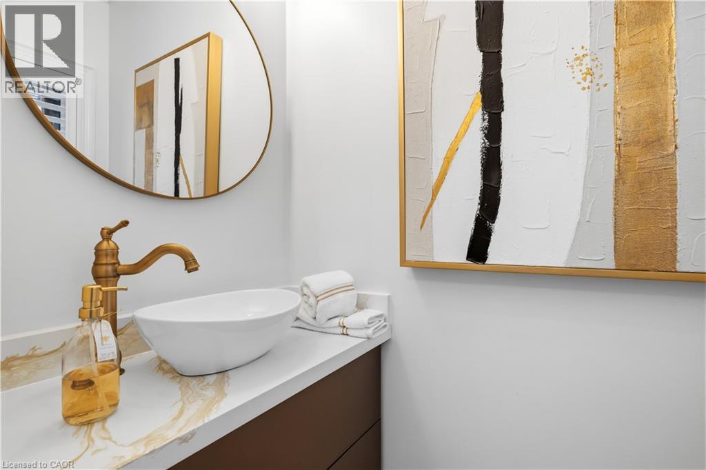 Vessel sink with a brass-finish faucet set on a white countertop with gold-veined detailing - 199 Hunter Street W, Hamilton, ON - Indoor Photo Showing Bathroom