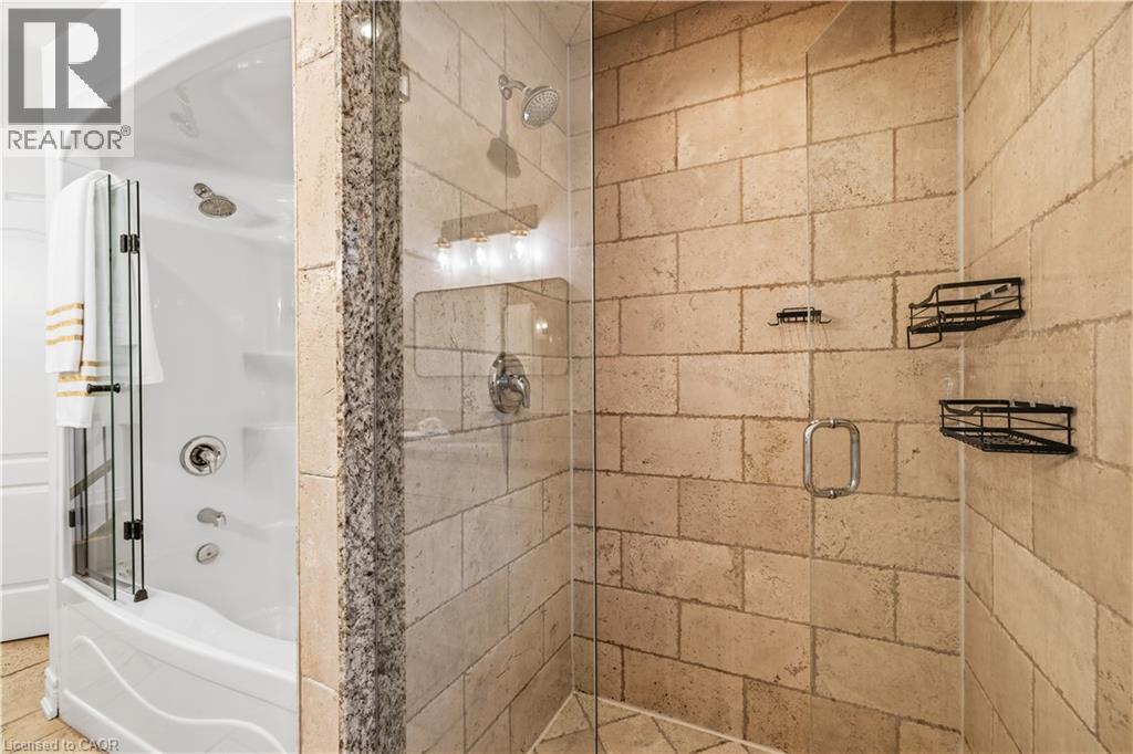 Shower enclosure with glass door, stone-look tile surround, and built-in shelving - 199 Hunter Street W, Hamilton, ON - Indoor Photo Showing Bathroom