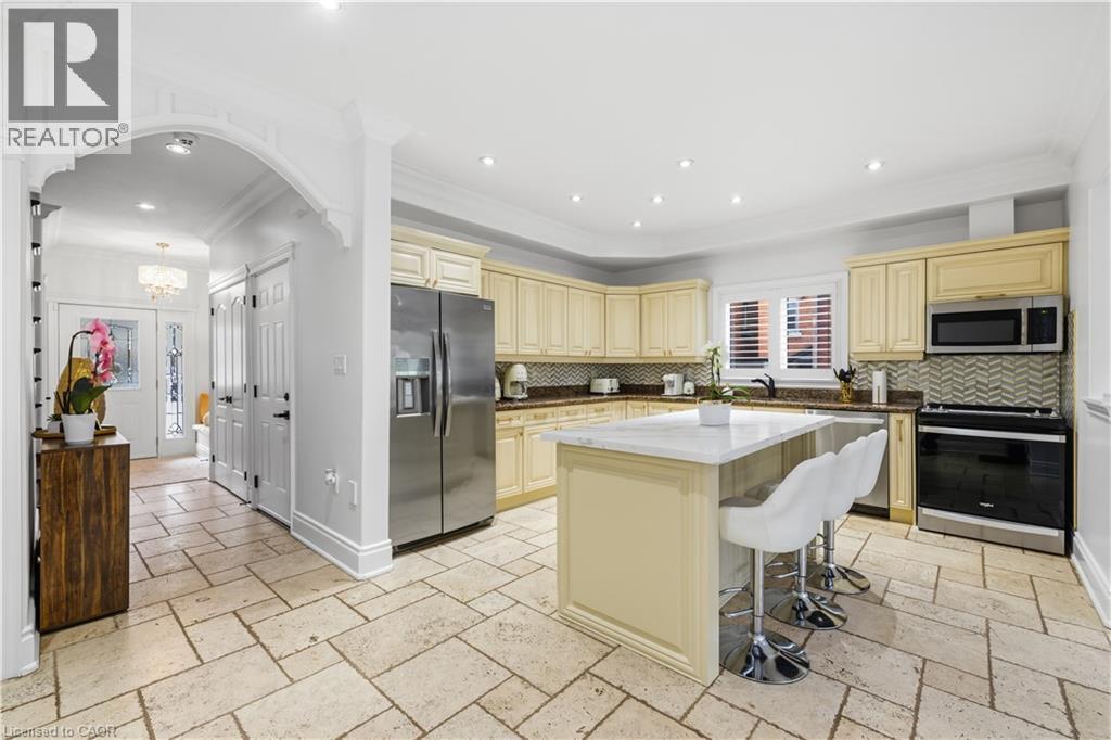 Spacious kitchen featuring light-toned cabinetry, stainless steel appliances, a center island with a stone countertop, and light-toned tile flooring - 199 Hunter Street W, Hamilton, ON - Indoor Photo Showing Kitchen