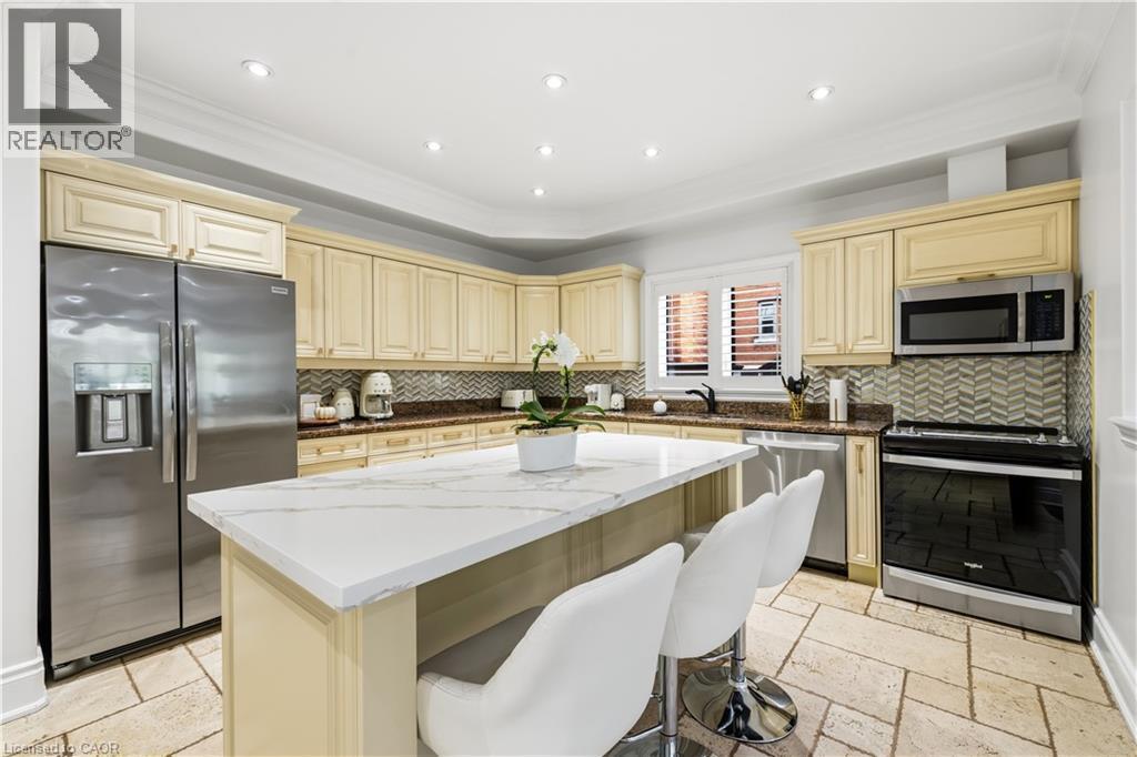 Kitchen featuring a large center island with a white countertop, stainless steel appliances, extensive cabinetry, a tiled backsplash, and recessed lighting - 199 Hunter Street W, Hamilton, ON - Indoor Photo Showing Kitchen