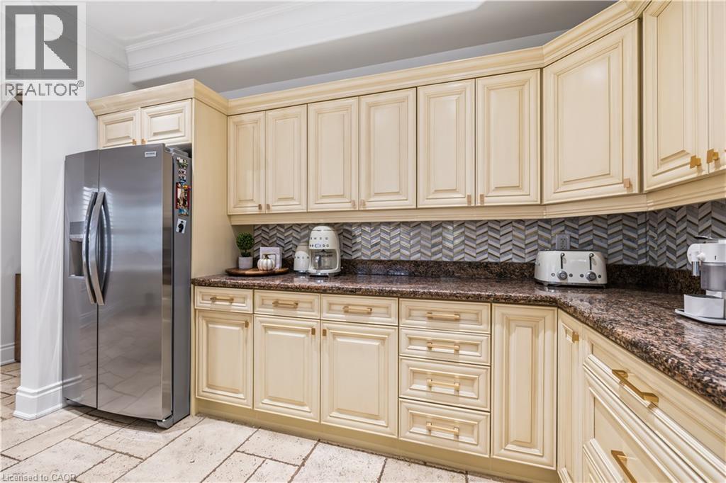 Kitchen featuring extensive cream-colored cabinetry, brown granite countertops, a mosaic tile backsplash, and stone tile flooring - 199 Hunter Street W, Hamilton, ON - Indoor Photo Showing Kitchen