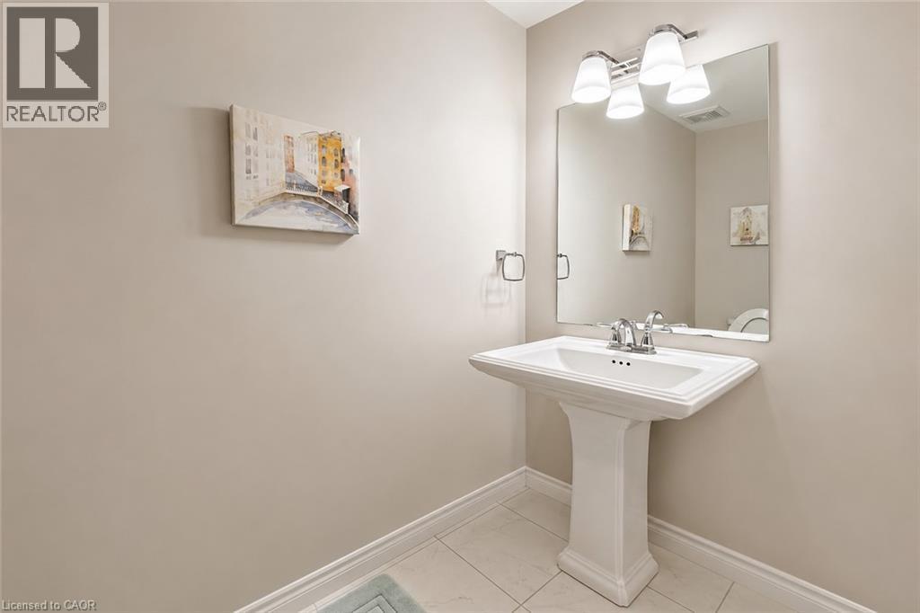Pedestal sink with chrome faucet, large vanity mirror, and three-light fixture - 133 St Leger Street, Kitchener, ON - Indoor Photo Showing Bathroom