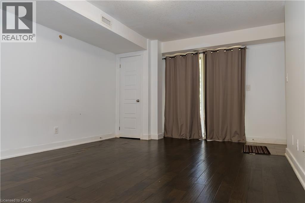 Room featuring dark wood-finish flooring, white walls, and a white five-panel interior door - 190 Century Hill Drive Unit# A5, Kitchener, ON - Indoor Photo Showing Other Room