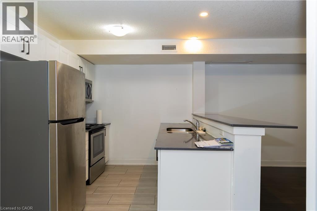 Kitchen featuring white cabinetry with dark hardware, stainless steel appliances, dark countertops, and tile flooring - 190 Century Hill Drive Unit# A5, Kitchener, ON - Indoor Photo Showing Kitchen