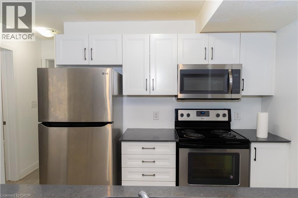 Contemporary kitchen featuring white cabinetry with dark hardware, dark countertops, and stainless steel appliances - 190 Century Hill Drive Unit# A5, Kitchener, ON - Indoor Photo Showing Kitchen