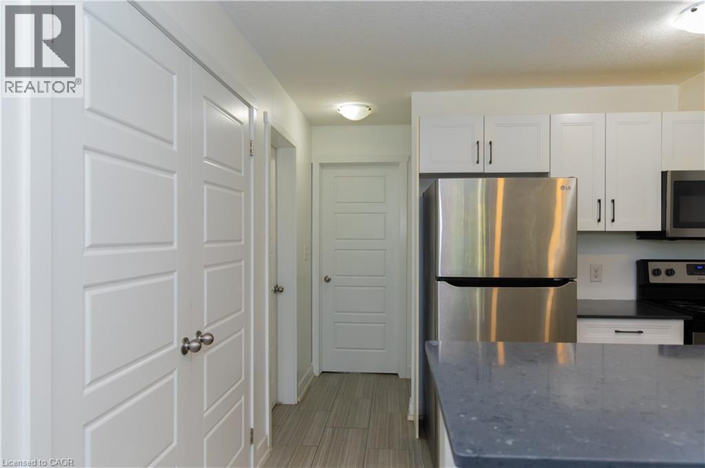 Contemporary kitchen featuring white cabinetry, stainless steel appliances, dark countertops, and light wood-finish flooring - 190 Century Hill Drive Unit# A5, Kitchener, ON - Indoor Photo Showing Kitchen