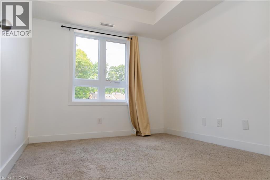 Carpeted room featuring a large window with white framing and a black curtain rod - 190 Century Hill Drive Unit# A5, Kitchener, ON - Indoor Photo Showing Other Room