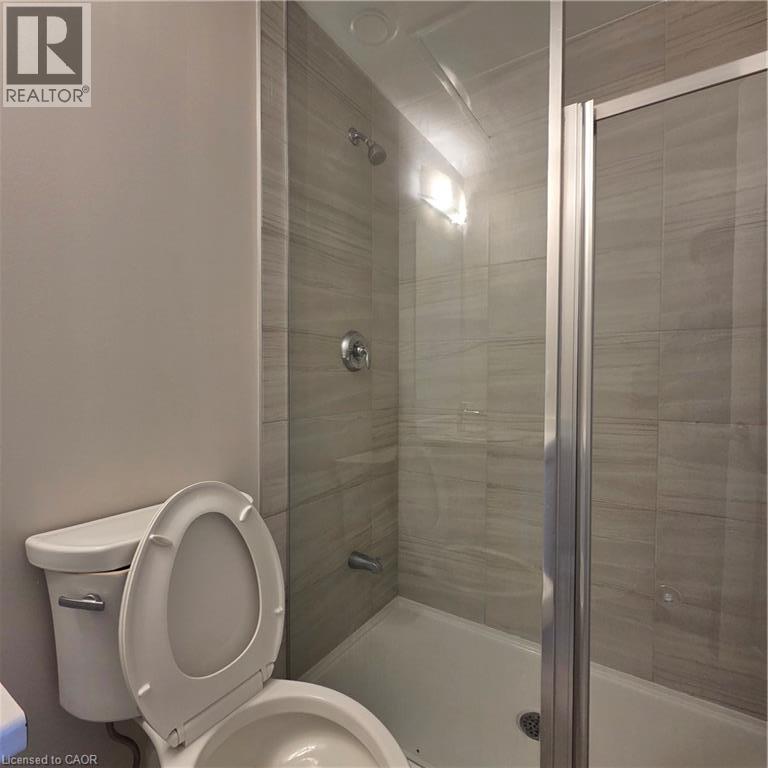 Shower enclosure with glass panel, chrome fixtures, and horizontal striped tile surround - 20 Palace Place Unit# E9, Kitchener, ON - Indoor Photo Showing Bathroom