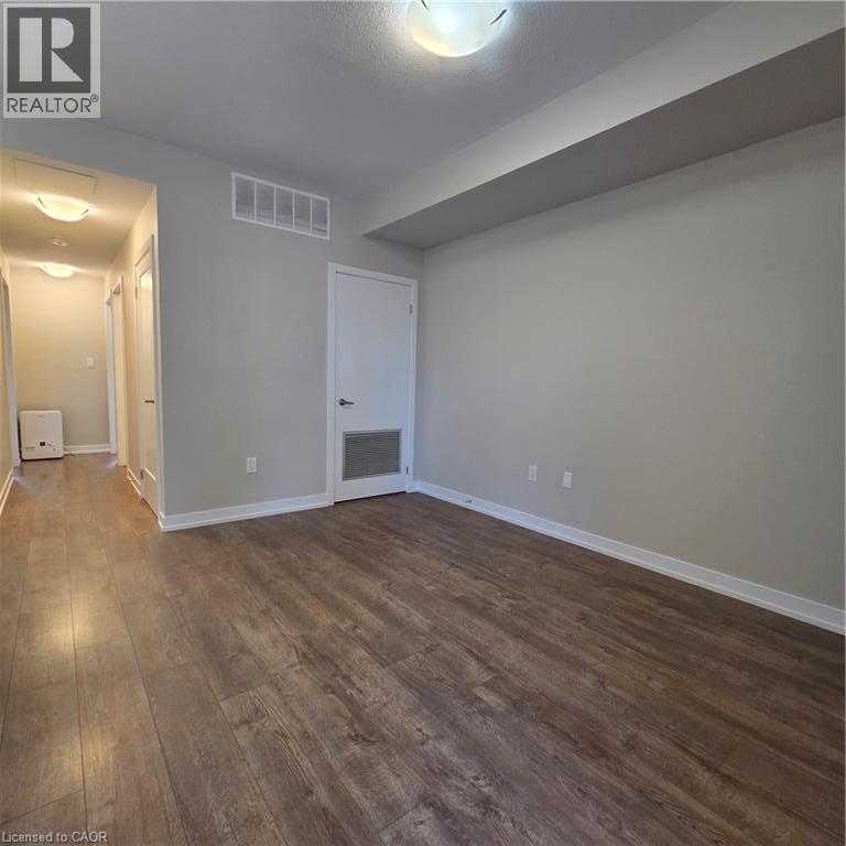 Spacious room featuring wood-finish flooring, light grey walls, and white baseboards - 20 Palace Place Unit# E9, Kitchener, ON - Indoor Photo Showing Other Room