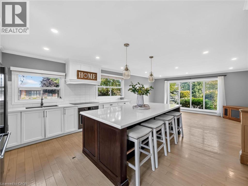 Spacious open-concept kitchen featuring a large central island with seating, white shaker cabinetry, white subway tile backsplash, and light wood-finish flooring - 143 Cromwell Crescent, Hamilton, ON - Indoor Photo Showing Kitchen With Upgraded Kitchen