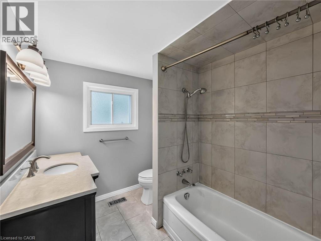 Bathroom featuring a single vanity with an integrated sink, a rectangular mirror, and an overhead light fixture - 143 Cromwell Crescent, Hamilton, ON - Indoor Photo Showing Bathroom