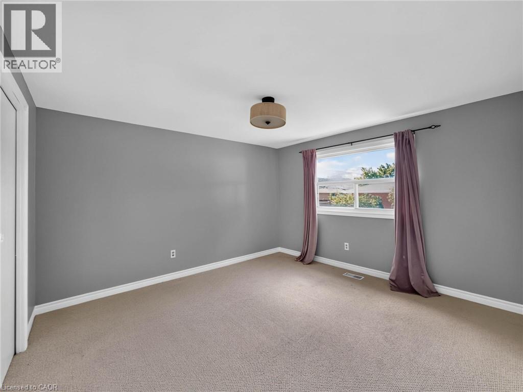 Carpeted room with a window providing natural light, grey painted walls, white trim, and a semi-flush ceiling fixture - 143 Cromwell Crescent, Hamilton, ON - Indoor Photo Showing Other Room