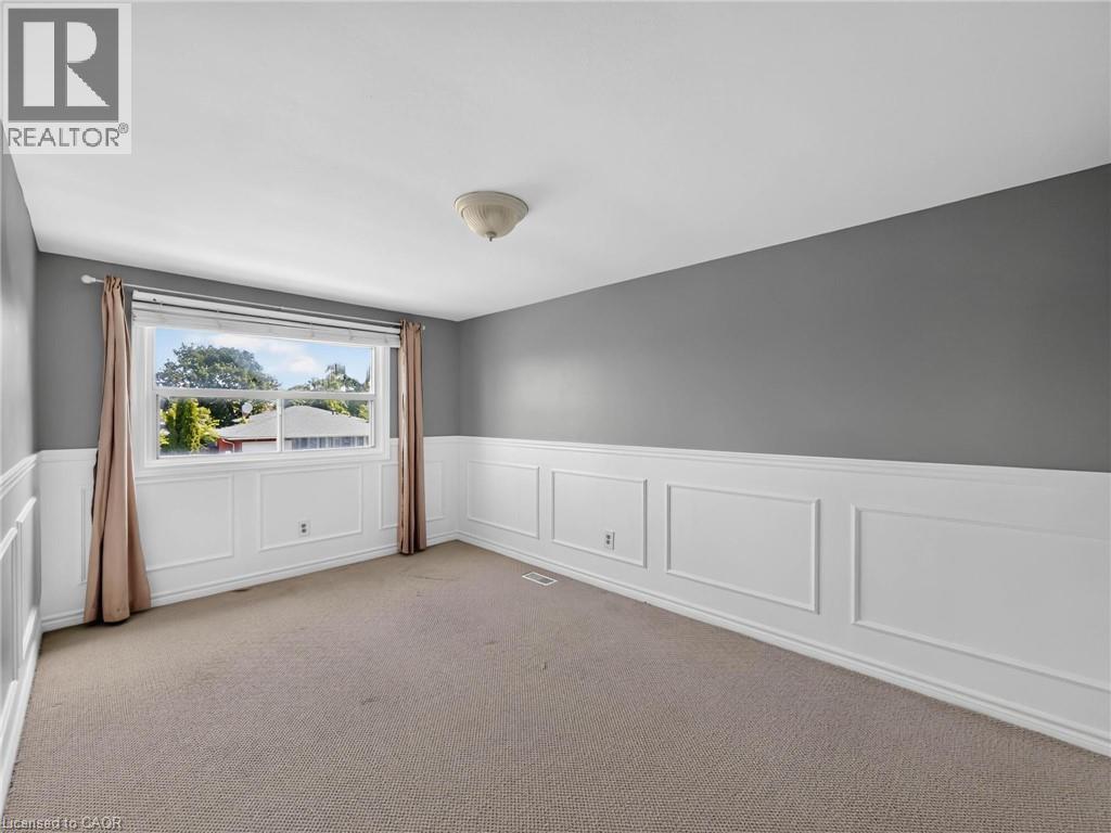 Room featuring wainscoting, neutral carpet, a large window, and a flush mount ceiling light - 143 Cromwell Crescent, Hamilton, ON - Indoor Photo Showing Other Room