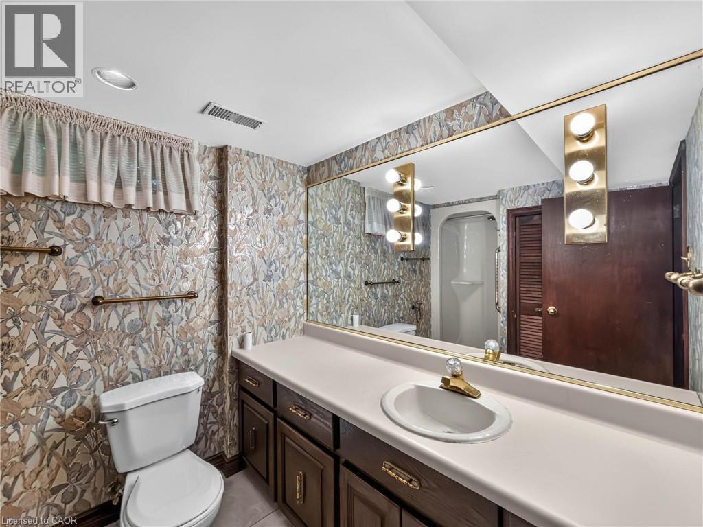 Bathroom featuring a vanity with an integrated sink, dark wood cabinetry, and a large wall-mounted mirror - 143 Cromwell Crescent, Hamilton, ON - Indoor Photo Showing Bathroom