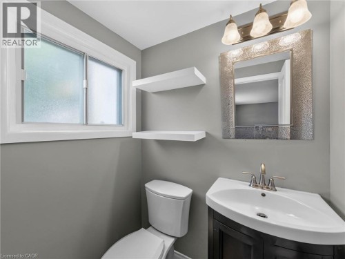 Powder room featuring a corner vanity with an integrated sink, a brushed nickel faucet, and a decorative framed mirror - 143 Cromwell Crescent, Hamilton, ON - Indoor Photo Showing Bathroom