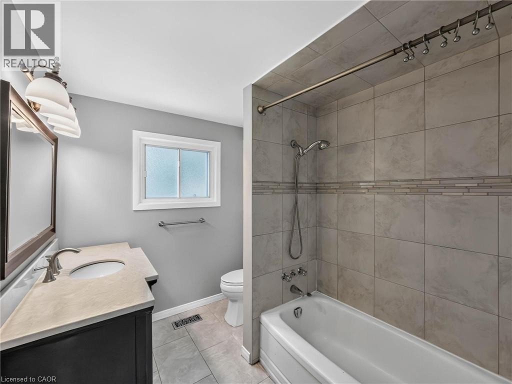 Bathroom featuring a single vanity with an integrated sink, a rectangular mirror, and an overhead light fixture - 143 Cromwell Crescent, Hamilton, ON - Indoor Photo Showing Bathroom