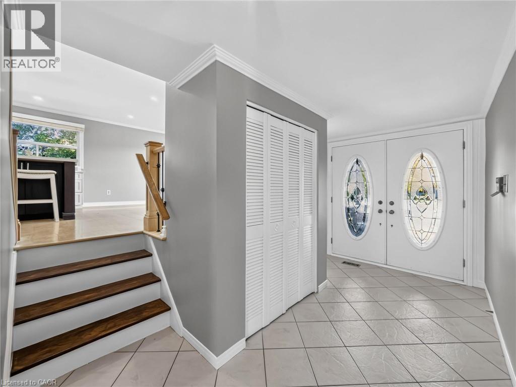 Entryway featuring double doors with decorative oval glass inserts, tile flooring, bi-fold closet doors, and crown molding - 143 Cromwell Crescent, Hamilton, ON - Indoor Photo Showing Other Room