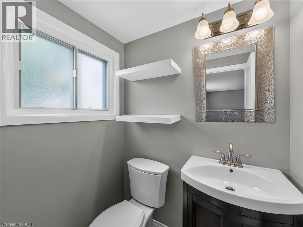 Powder room featuring a corner vanity with an integrated sink, a brushed nickel faucet, and a decorative framed mirror - 143 Cromwell Crescent, Hamilton, ON - Indoor Photo Showing Bathroom
